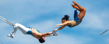 Load image into Gallery viewer, Anthony Pages, left, readies himself to catch his airborne wife, Vanya, 60 feet above the ground during their trapeze act, Aug. 27, 2023, at the Colorado State Fair in Pueblo. (Mike Sweeney, Special to The Colorado Sun)
